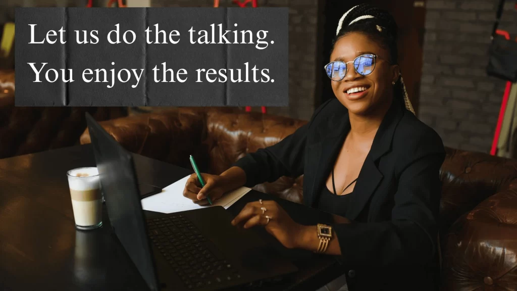 A confident Black woman in a sleek suit smiling in a modern office space, wearing glasses, with text beside her that reads “We do the work, you enjoy the results.”